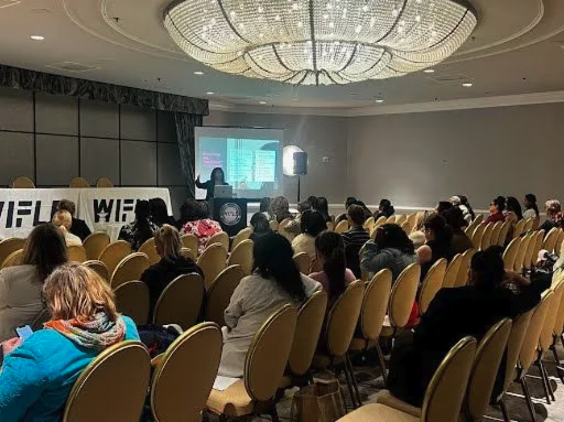 A full ballroom audience watching Qiana present
